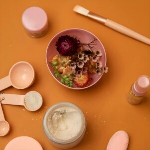 Cosmetic ingredients and tools arranged on an orange surface.